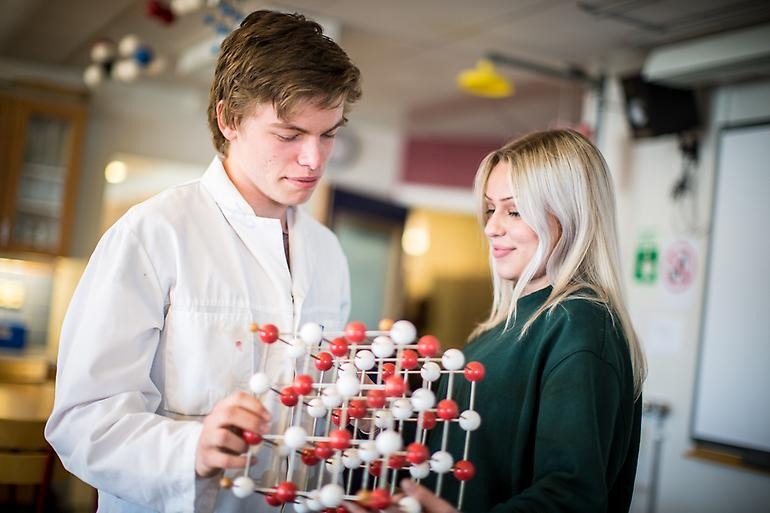Två studenter diskuterar en molekylmodell