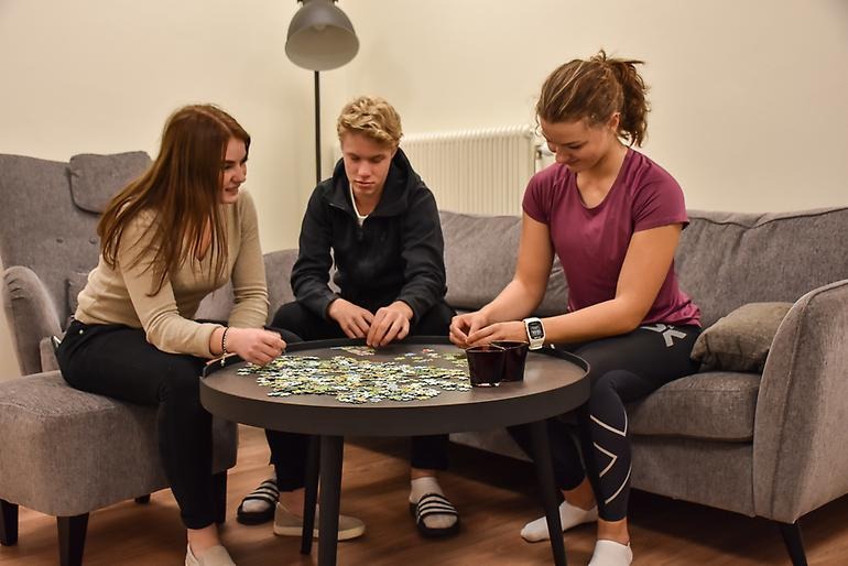 Tre elever som pusslar vid ett bord.