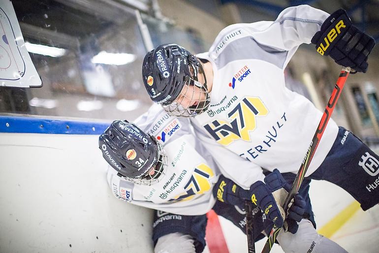 Två hockeyspelare i en kampsituation vid sargen.